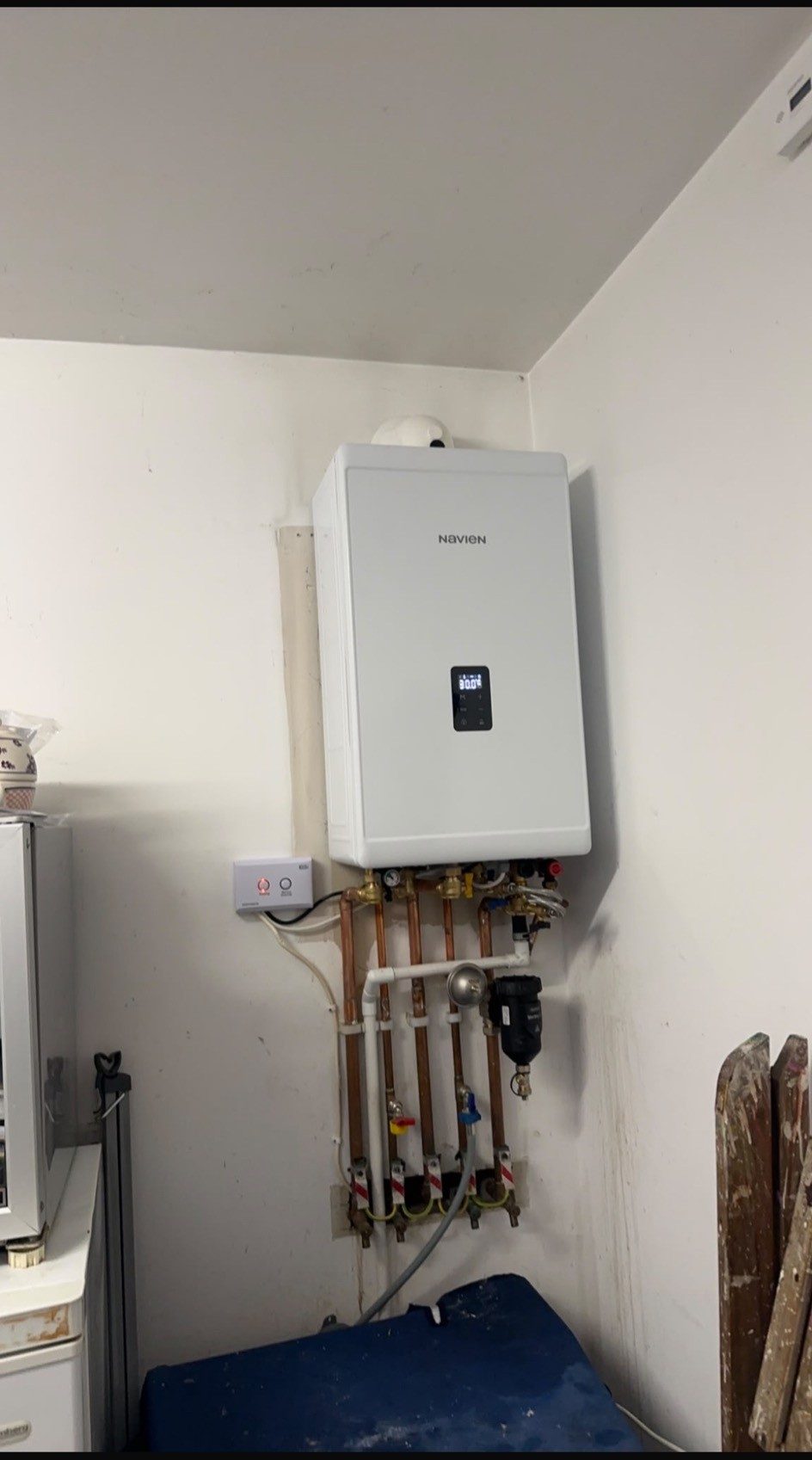 A newly installed Navien combi boiler on a kitchen wall with copper pipework, filter and isolation valves