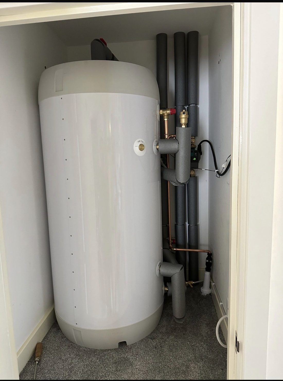 An unvented hot water cylinder fitted in a cupboard with insulated pipework and a thermostatic mixing valve
